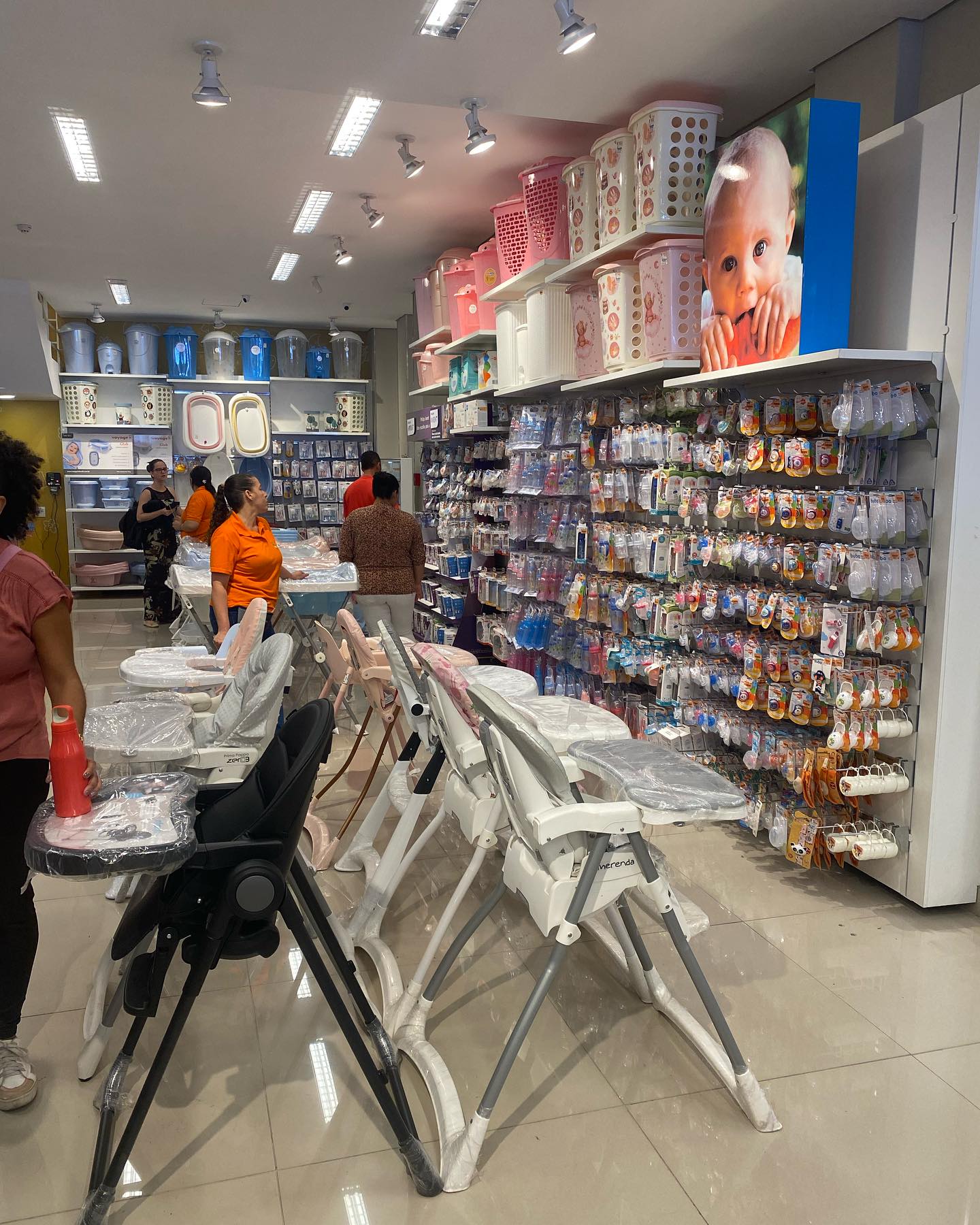 Corredor da loja com araras e prateleiras de roupa infantil